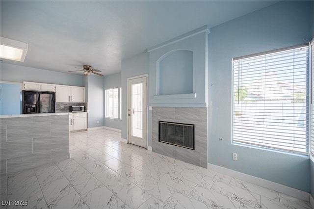 6524 Rain Forest Dr, Las Vegas, NV 89108 - unfurnished living room featuring ceiling fan, light marble finish floors, and a tiled fireplace