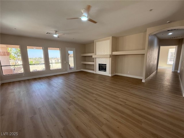 379 Marlin Cove Rd, Henderson, NV 89012 - unfurnished living room featuring arched walkways, dark wood finished floors, ceiling fan, a fireplace, and built in features