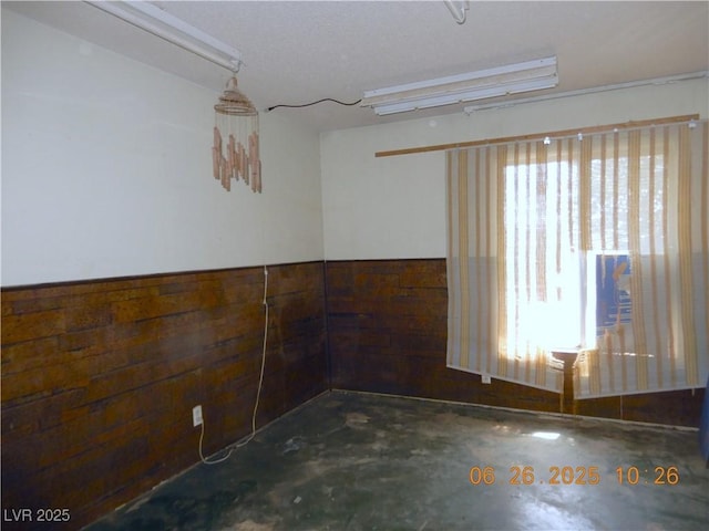 3175 Palmdale St, Las Vegas, NV 89121 - unfurnished room featuring unfinished concrete floors, wood walls, and a wainscoted wall