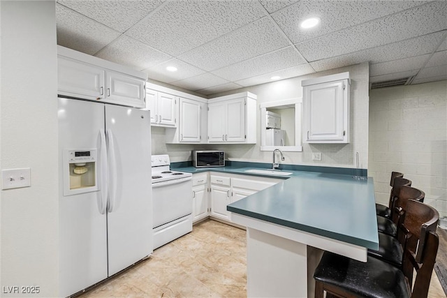 3930 Maranatha Cir, Las Vegas, NV 89103 - kitchen with white appliances, white cabinetry, a peninsula, a paneled ceiling, and a breakfast bar area