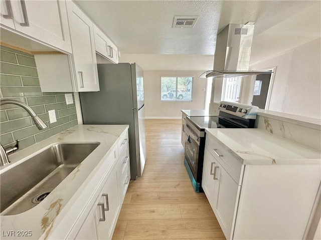 604 N Minnesota St, Las Vegas, NV 89107 - kitchen featuring appliances with stainless steel finishes, island exhaust hood, light wood finished floors, white cabinetry, and a textured ceiling