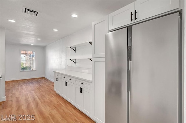 3907 Torsby Pl, Las Vegas, NV 89119 - kitchen with stainless steel refrigerator, open shelves, white cabinetry, light wood finished floors, and recessed lighting