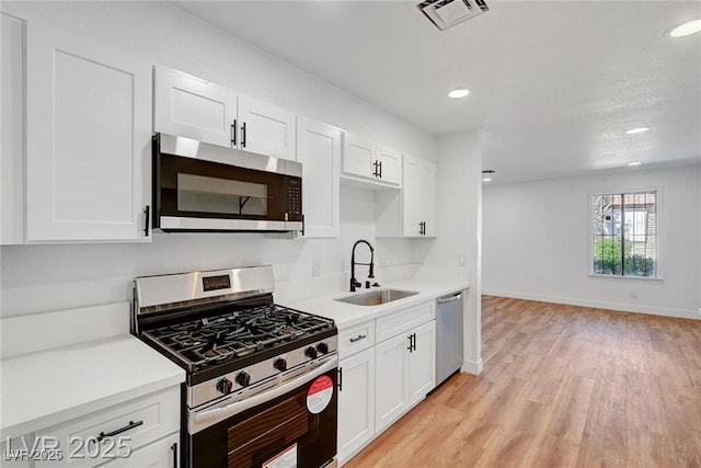 3907 Torsby Pl, Las Vegas, NV 89119 - kitchen featuring appliances with stainless steel finishes, light countertops, light wood-type flooring, white cabinets, and recessed lighting