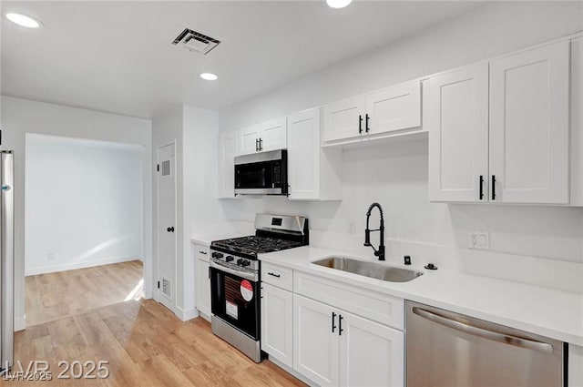 3907 Torsby Pl, Las Vegas, NV 89119 - kitchen featuring appliances with stainless steel finishes, white cabinetry, light countertops, light wood-style floors, and recessed lighting