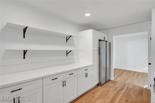 3907 Torsby Pl, Las Vegas, NV 89119 - kitchen featuring open shelves, freestanding refrigerator, white cabinets, light wood-style floors, and light countertops