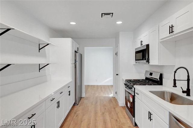 3907 Torsby Pl, Las Vegas, NV 89119 - kitchen with stainless steel appliances, open shelves, light wood-type flooring, white cabinets, and recessed lighting