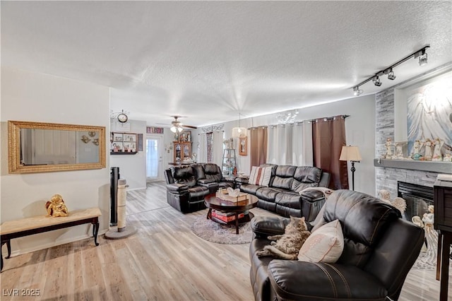700 Capri Dr Unit 27B, Boulder City, NV 89005 - living room featuring a textured ceiling, a stone fireplace, track lighting, wood finished floors, and a ceiling fan