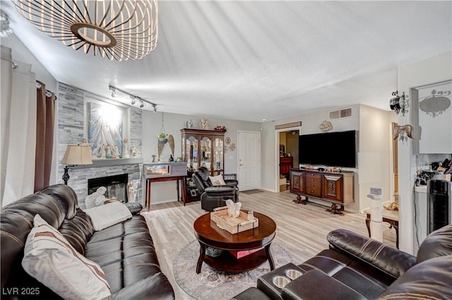 700 Capri Dr Unit 27B, Boulder City, NV 89005 - living area with light wood finished floors, a stone fireplace, a chandelier, and rail lighting