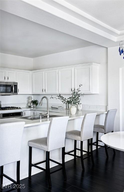 9430 Laguna Niguel Dr Unit 203, Las Vegas, NV 89134 - kitchen featuring stainless steel appliances, white cabinets, a breakfast bar area, and dark wood finished floors