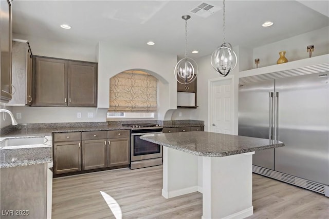 9784 Kodiak Island Ct, Las Vegas, NV 89141 - kitchen featuring appliances with stainless steel finishes, a chandelier, light wood-type flooring, light stone counters, and a kitchen island