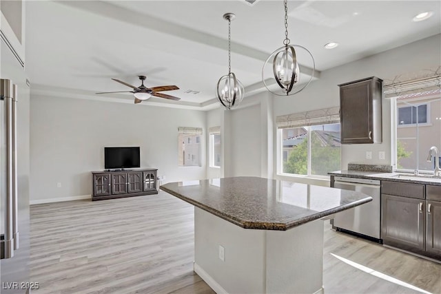 9784 Kodiak Island Ct, Las Vegas, NV 89141 - kitchen with stainless steel dishwasher, dark brown cabinets, light wood finished floors, dark stone countertops, and a chandelier