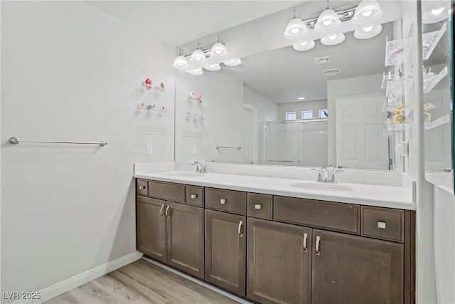 9784 Kodiak Island Ct, Las Vegas, NV 89141 - bathroom with double vanity, an enclosed shower, and wood finished floors