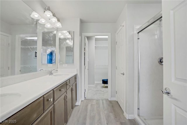 9784 Kodiak Island Ct, Las Vegas, NV 89141 - bathroom with a shower stall, a walk in closet, wood finished floors, and double vanity
