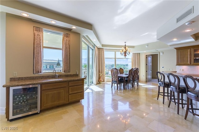 9101 Alta Dr Unit 301, Las Vegas, NV 89145 - kitchen with wine cooler, a chandelier, dark countertops, tasteful backsplash, and brown cabinetry