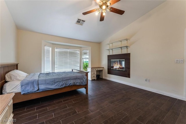 7720 W Agate Ave, Las Vegas, NV 89113 - bedroom featuring dark wood-style flooring, vaulted ceiling, a glass covered fireplace, and ceiling fan