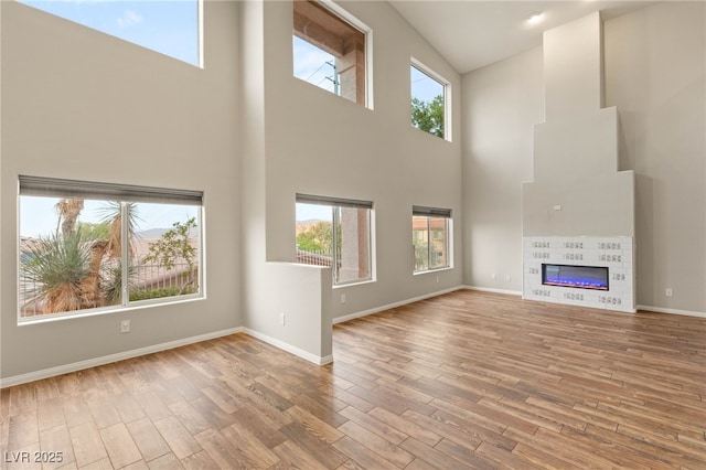 251 Big Horn Dr, Boulder City, NV 89005 - unfurnished living room with a towering ceiling, healthy amount of natural light, wood finished floors, and a fireplace