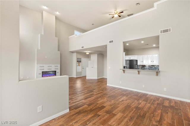 251 Big Horn Dr, Boulder City, NV 89005 - unfurnished living room featuring dark wood-style floors, a high ceiling, a ceiling fan, a tile fireplace, and crown molding