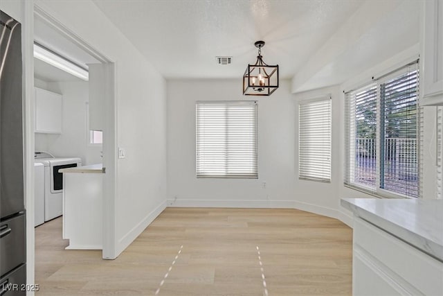 8924 Signal Terrace Dr, Las Vegas, NV 89134 - unfurnished dining area featuring washing machine and clothes dryer, light wood finished floors, and a chandelier