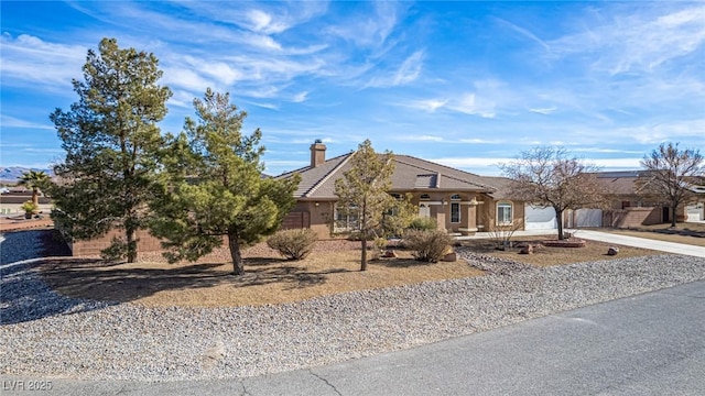 6781 Southgate St, Pahrump, NV 89061 - view of property hidden behind natural elements with concrete driveway, a chimney, and stucco siding