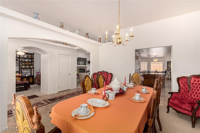 6781 Southgate St, Pahrump, NV 89061 - dining area featuring arched walkways, a chandelier, a high ceiling, a fireplace, and carpet flooring