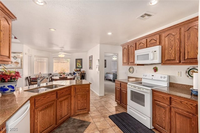 6781 Southgate St, Pahrump, NV 89061 - kitchen featuring white appliances, ceiling fan, brown cabinets, stone counters, and light tile patterned floors