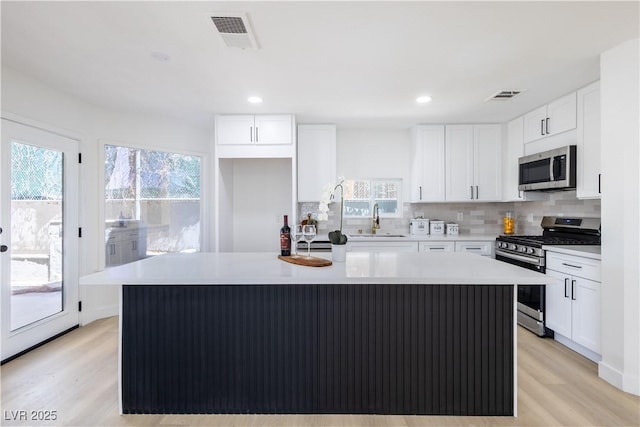5264 Silverheart Ave, Las Vegas, NV 89142 - kitchen with appliances with stainless steel finishes, tasteful backsplash, healthy amount of natural light, white cabinetry, and recessed lighting