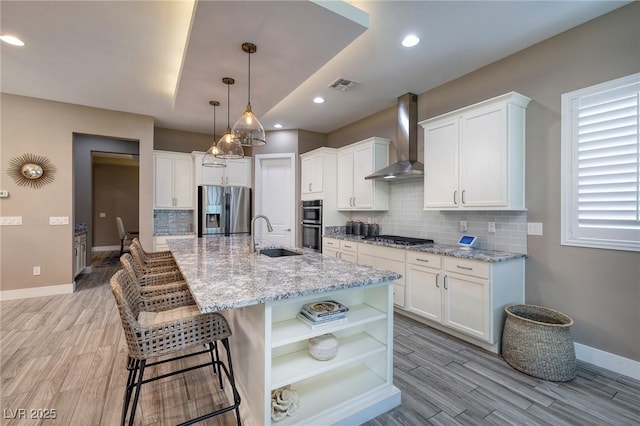 10349 Bressana Dr, Las Vegas, NV 89135 - kitchen with stainless steel appliances, wall chimney exhaust hood, light wood finished floors, backsplash, and open shelves