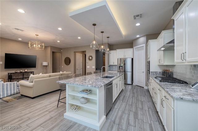10349 Bressana Dr, Las Vegas, NV 89135 - kitchen with appliances with stainless steel finishes, open shelves, light wood finished floors, open floor plan, and recessed lighting