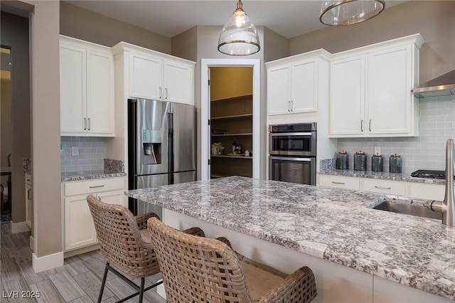 10349 Bressana Dr, Las Vegas, NV 89135 - kitchen featuring appliances with stainless steel finishes, a kitchen bar, white cabinets, and backsplash