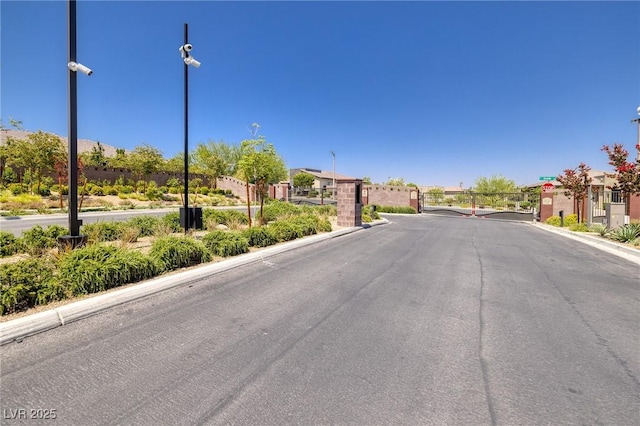 10349 Bressana Dr, Las Vegas, NV 89135 - view of asphalt road featuring a gate, a residential view, a gated entry, curbs, and street lights