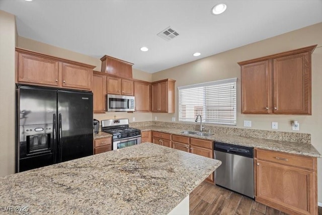 7028 Weavers Pl, North Las Vegas, NV 89084 - kitchen with appliances with stainless steel finishes, light stone counters, dark wood-style floors, recessed lighting, and brown cabinetry