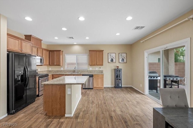 7028 Weavers Pl, North Las Vegas, NV 89084 - kitchen with stainless steel appliances, light wood finished floors, a center island, recessed lighting, and light stone counters
