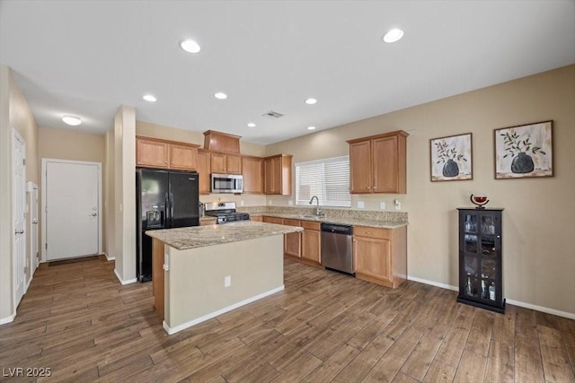 7028 Weavers Pl, North Las Vegas, NV 89084 - kitchen featuring stainless steel appliances, wood finished floors, a center island, recessed lighting, and light stone countertops