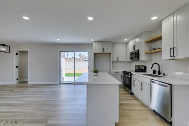 6100 Fawn Cir, Las Vegas, NV 89107 - kitchen with appliances with stainless steel finishes, open shelves, a center island, light wood-style floors, and recessed lighting