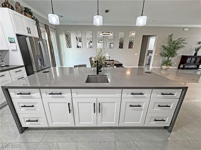 2891 S Rainbow Ave, Pahrump, NV 89048 - kitchen featuring stainless steel fridge with ice dispenser, ornamental molding, light marble finish floors, an island with sink, and dark stone counters