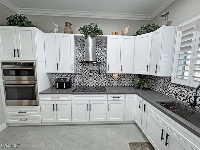 2891 S Rainbow Ave, Pahrump, NV 89048 - kitchen with black electric stovetop, double oven, dark countertops, wall chimney range hood, and crown molding