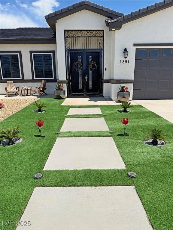 2891 S Rainbow Ave, Pahrump, NV 89048 - doorway to property featuring stucco siding, an attached garage, and a lawn