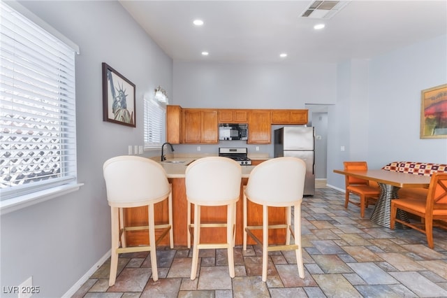 1012 Greystone Dr, Las Vegas, NV 89108 - kitchen featuring appliances with stainless steel finishes, light stone finish flooring, a peninsula, light countertops, and a breakfast bar area