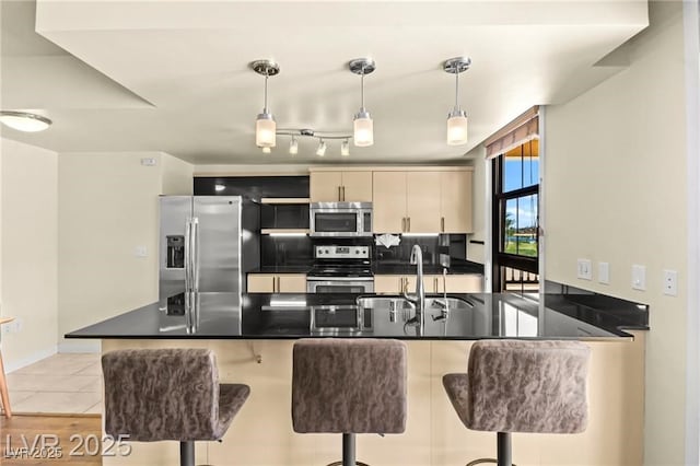 29 Montelago Blvd Unit 131, Henderson, NV 89011 - kitchen featuring appliances with stainless steel finishes, dark countertops, a peninsula, a breakfast bar, and decorative light fixtures