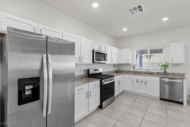 9054 Tangerine Tree Ct, Las Vegas, NV 89113 - kitchen featuring appliances with stainless steel finishes, white cabinetry, light stone counters, light tile patterned floors, and recessed lighting
