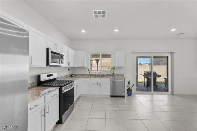 9054 Tangerine Tree Ct, Las Vegas, NV 89113 - kitchen featuring appliances with stainless steel finishes, light stone countertops, white cabinets, recessed lighting, and light tile patterned flooring