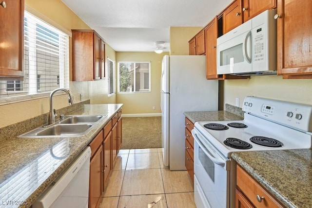 1836 N Decatur Blvd Unit 203, Las Vegas, NV 89108 - kitchen featuring white appliances, brown cabinets, a ceiling fan, light tile patterned floors, and light carpet