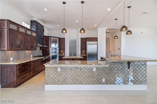 1319 Red Baron Ln, Boulder City, NV 89005 - kitchen with appliances with stainless steel finishes, a large island with sink, crown molding, under cabinet range hood, and decorative light fixtures
