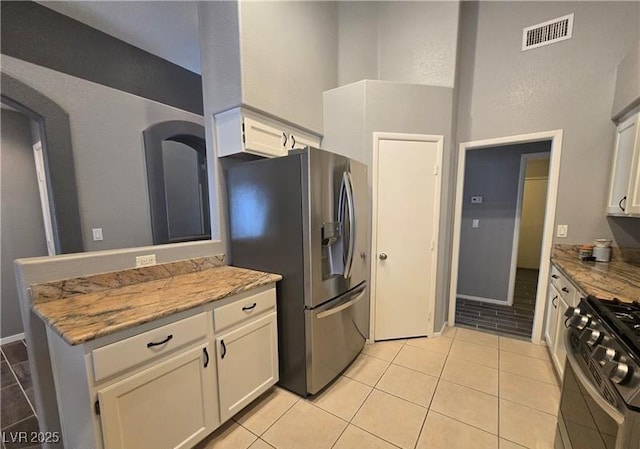 5121 Backwoodsman Ave, Las Vegas, NV 89130 - kitchen featuring stainless steel appliances, white cabinets, light stone countertops, and a high ceiling