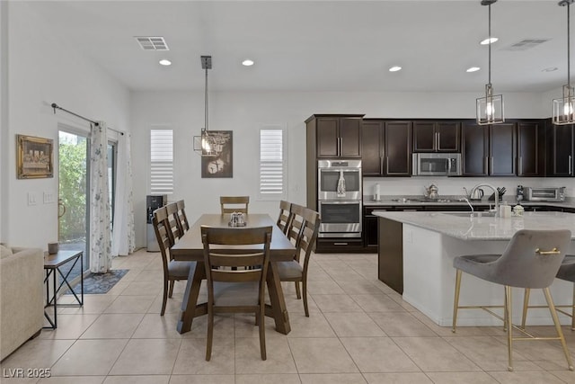 10181 Mount Harlow Ct, Las Vegas, NV 89141 - kitchen featuring stainless steel appliances, dark brown cabinetry, light stone countertops, hanging light fixtures, and recessed lighting