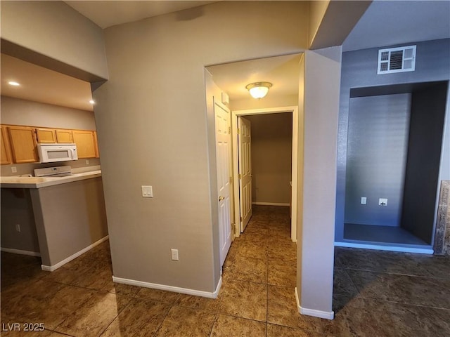 10231 Deerfield Beach Ave Unit 104, Las Vegas, NV 89129 - kitchen with white microwave, range, light countertops, and tile patterned floors
