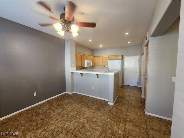 10231 Deerfield Beach Ave Unit 104, Las Vegas, NV 89129 - kitchen featuring white appliances, a peninsula, ceiling fan, light countertops, and light brown cabinets