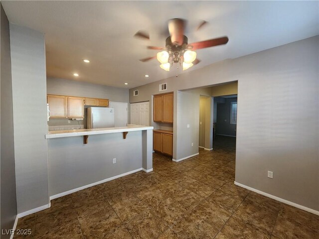 10231 Deerfield Beach Ave Unit 104, Las Vegas, NV 89129 - kitchen with freestanding refrigerator, a ceiling fan, a breakfast bar, a peninsula, and recessed lighting