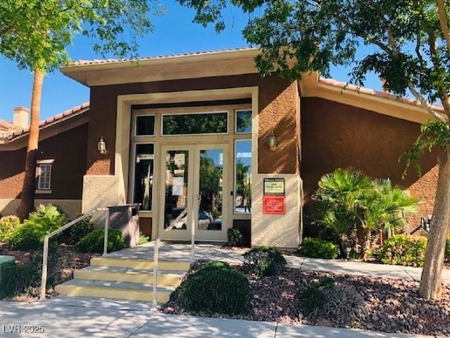 10231 Deerfield Beach Ave Unit 104, Las Vegas, NV 89129 - view of exterior entry with french doors, stucco siding, and a tile roof
