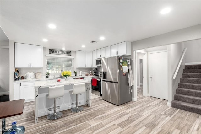 7135 Polaris Ave, Las Vegas, NV 89118 - kitchen with stainless steel appliances, white cabinetry, a center island, a breakfast bar area, and recessed lighting